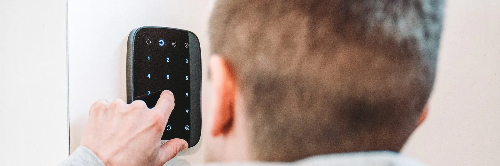 Iemand voert een code in op een digitaal toegangscontrolepaneel met nummertoetsen aan een deur