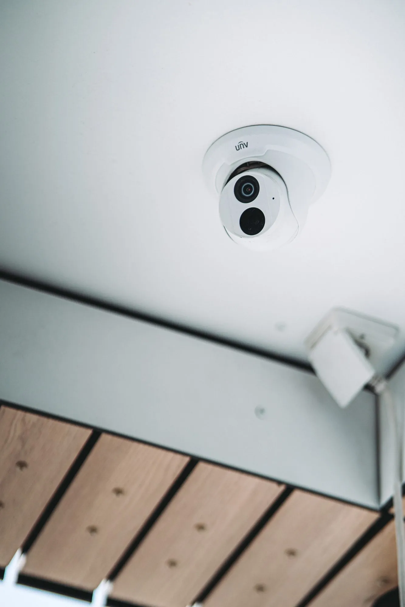 Witte beveiligingscamera met twee lenzen gemonteerd aan het plafond, voorzien van infrarood voor nachtbewaking
