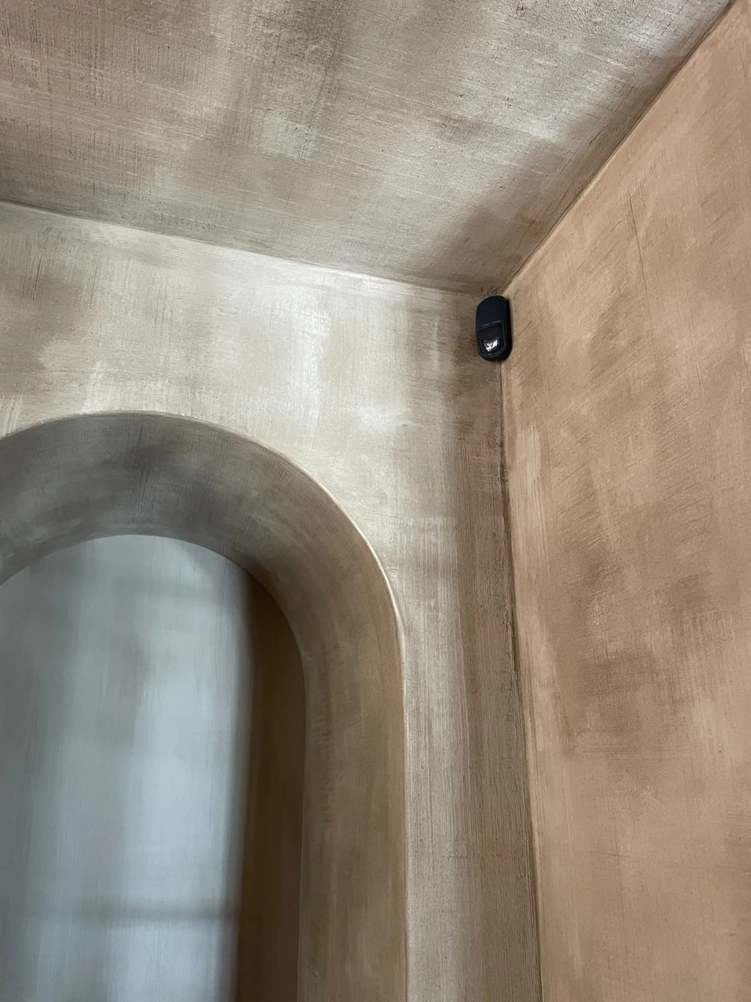 Bewegingsmelder op muur boven toilet in badkamer met betonnen plafond en houten wanden