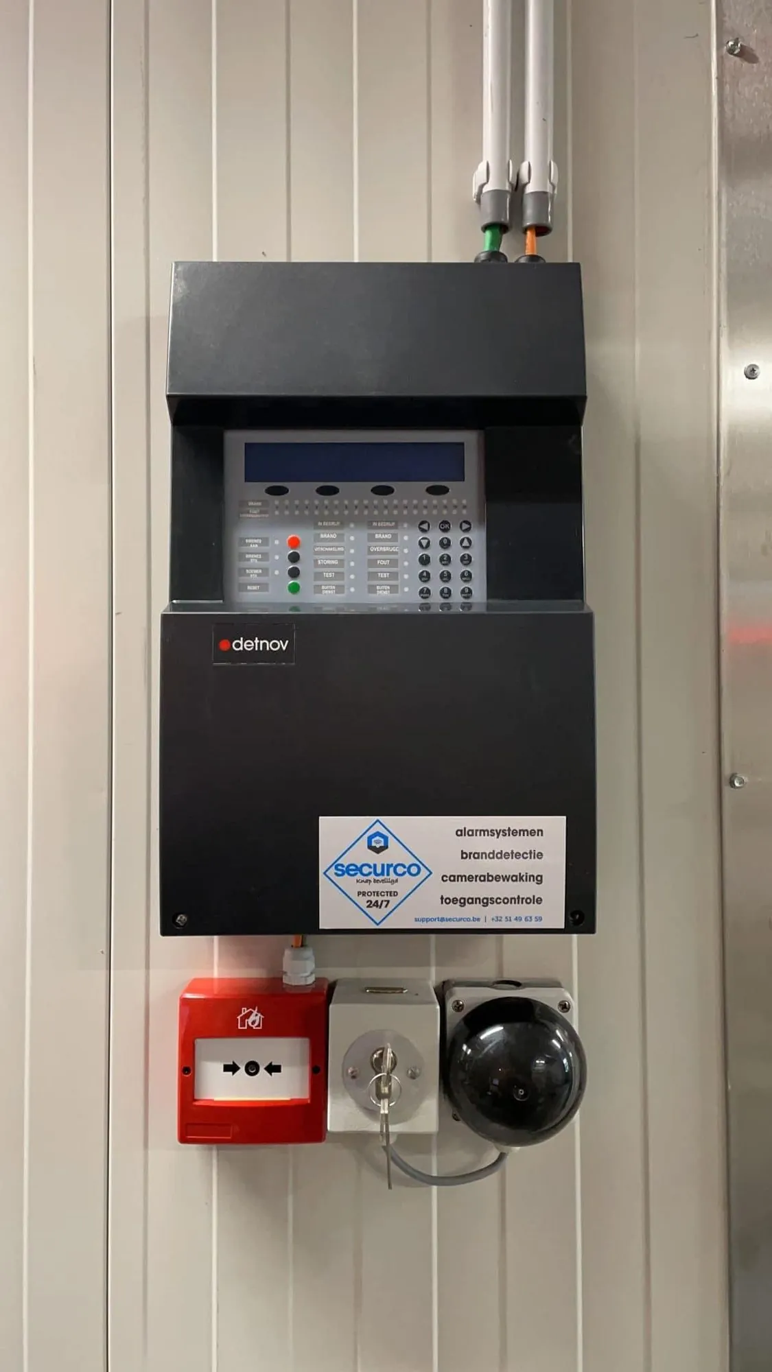 Branddetectie- en alarmsysteem van SecurCo aan de wand, met bedieningspaneel, noodknop en camerabewaking voor 24/7 bescherming