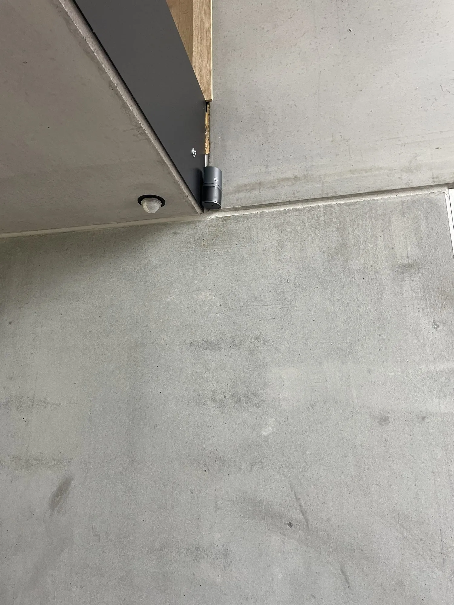 Beveiligingscamera en bewegingsmelder geïnstalleerd aan het plafond van een betonnen ruimte.