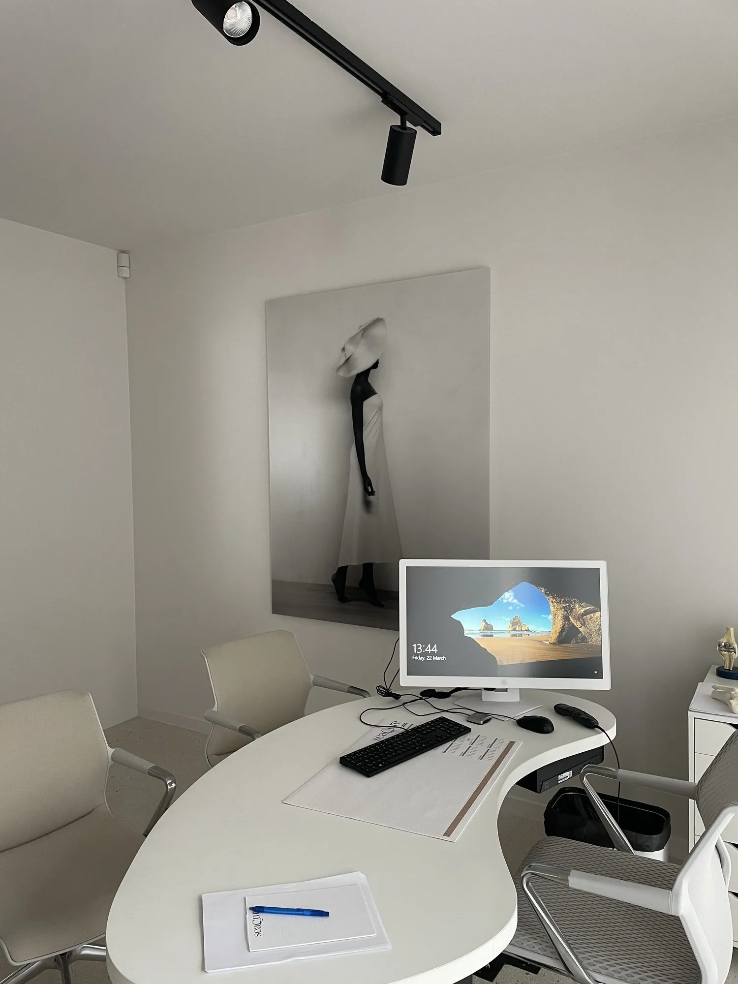 Modern kantoor met camerabewakingssysteem: moniteur toont bewakingsbeelden, zwart spotlicht aan plafond, witte werkplek