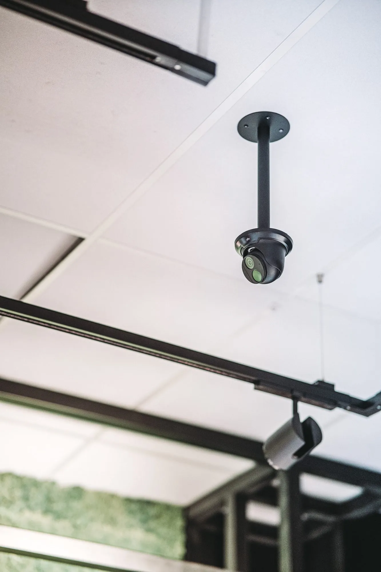 Zwarte beveiligingscamera met infraroodlenzen aan een plafond bevestigd met een steunarmpje