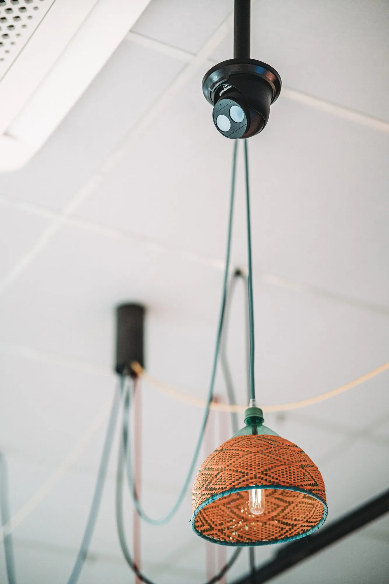 Zwarte koepelcamera aan plafond bevestigd met groene bekabeling, geïnstalleerd in een witte ruimte