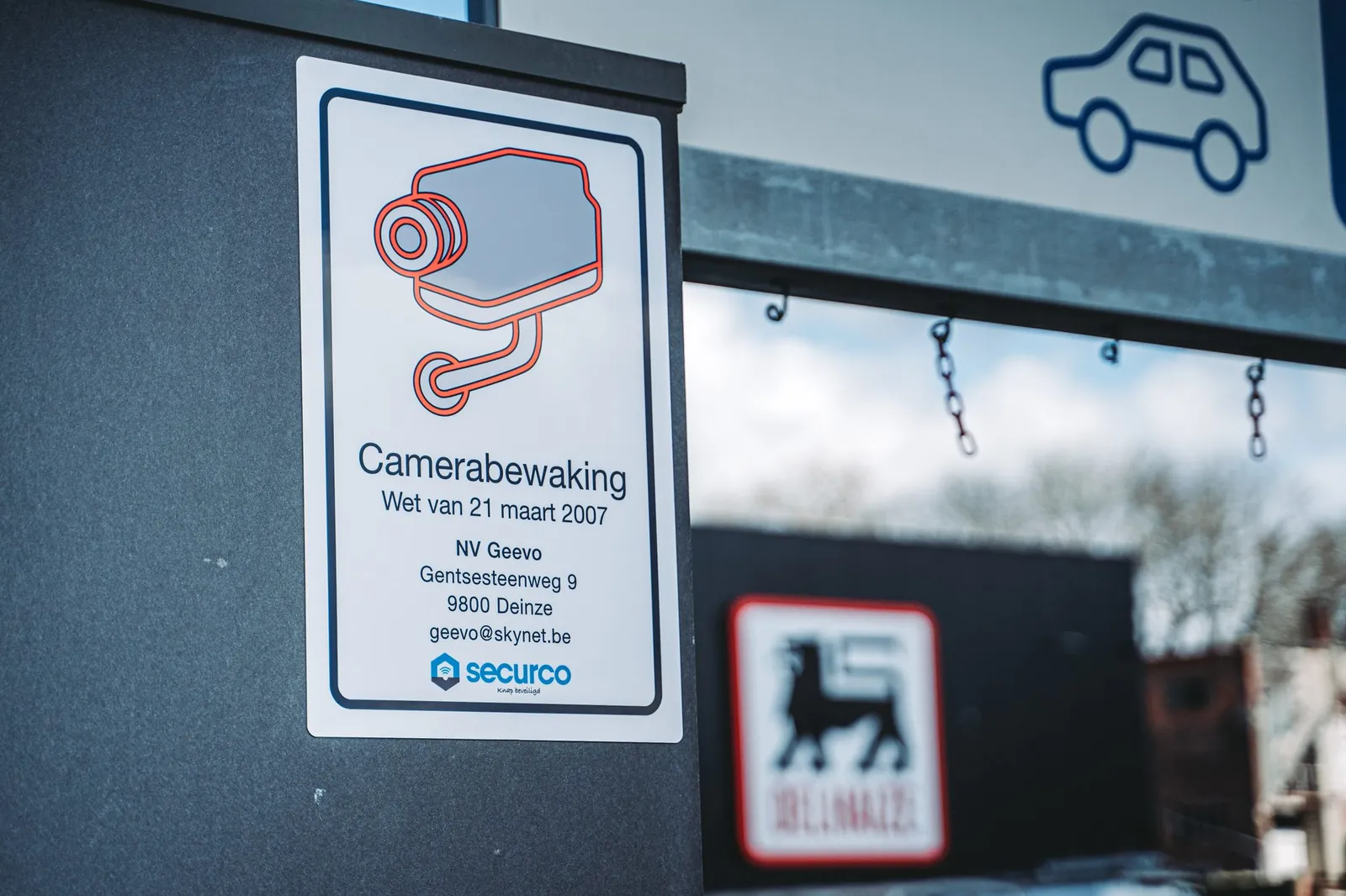 Waarschuwingsbord met camerabewakingssticker op een parkeerplaats, met SecurCo-logo zichtbaar