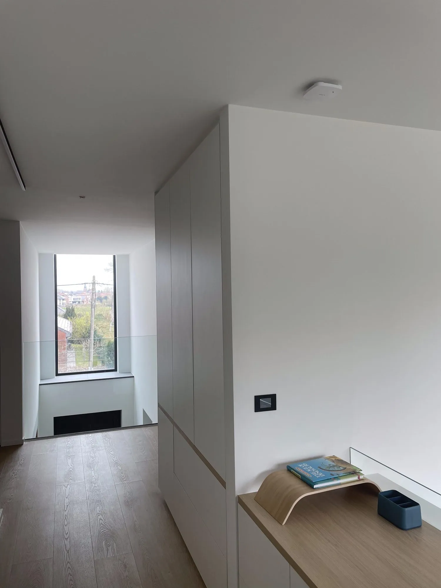 Moderne interieur met raam, witte wanden en een inbouwschakelaar, zicht op landschap buiten