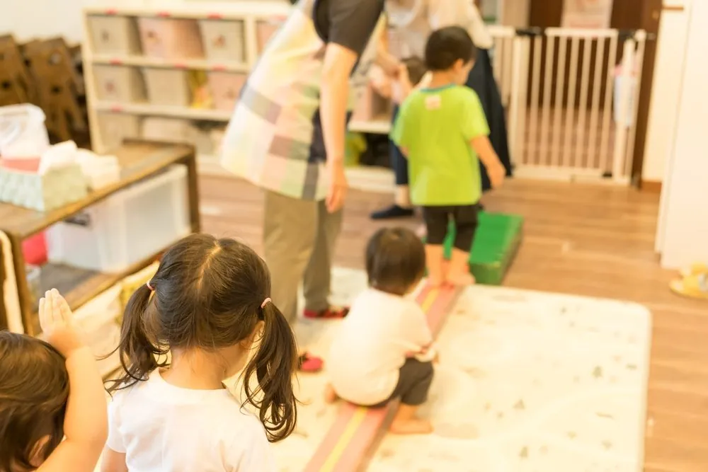 Kinderen spelen en bewegen zich in een zaal met houten vloer onder toezicht van volwassenen