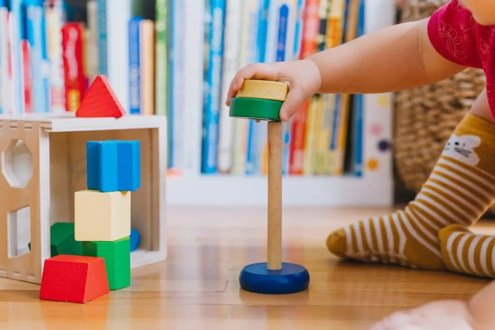 Kind speelt met gekleurde houten bouwblokken en stapelspel in een veilige speelruimte