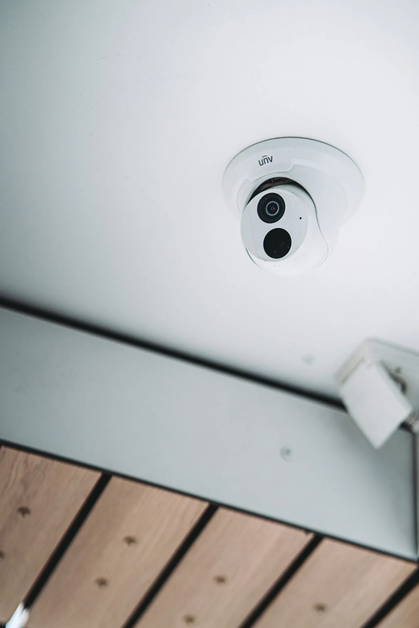 Witte dome-camera met twee lenzen gemonteerd aan het plafond voor bewaking van binnenruimtes